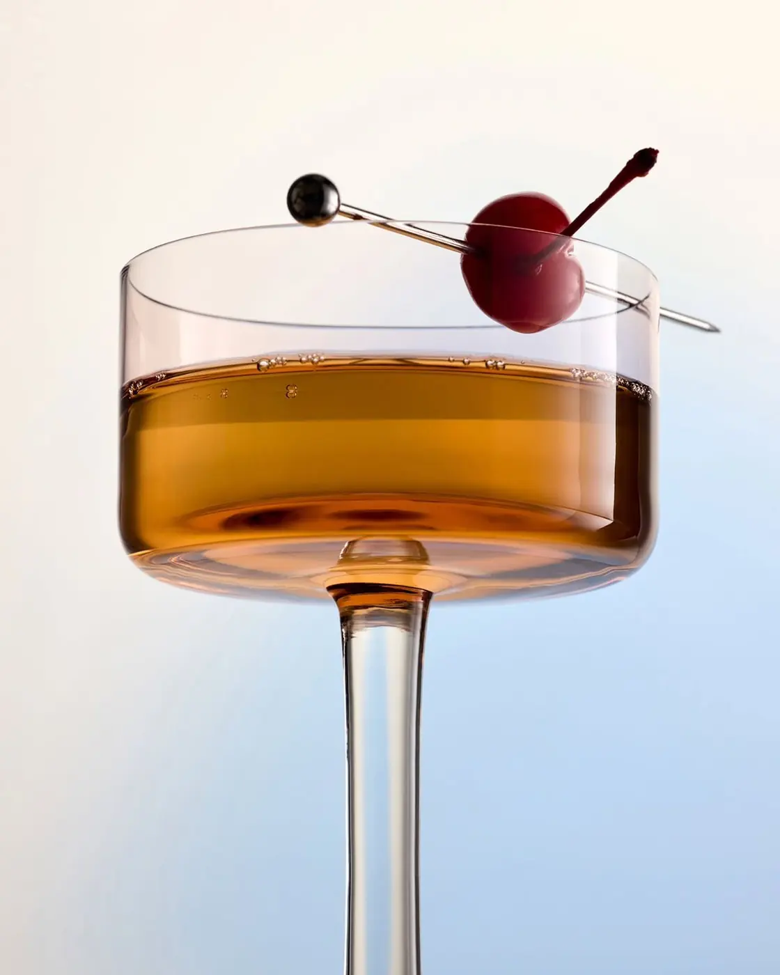 A finished amber cocktail with a cherry